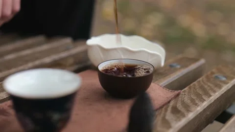 Close-up dark pu-erh is poured into bowls for tea. Chinese tea ceremony Stock Footage 229861119
