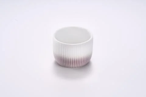 Close-up of dark red striped ceramic tea cup on white background Stockfoto's