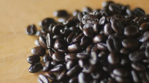 Close up of dark roasted coffee beans spinning on a wooden board Stock Footage 63209739