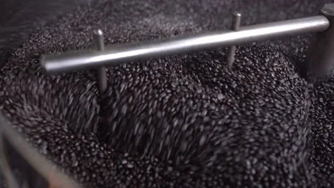 Close up of dark roasted coffee grains being mixed inside of a roaster machine Stock Footage 219592280