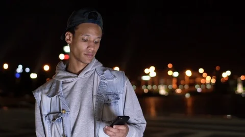 Close-up dark-skinned guy in blue jacket chatting on his smartphone Stock Footage 115739242