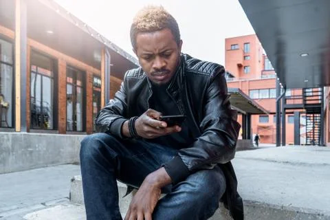 Close up of dark-skinned man looking at mobile phone screen. Stock Photos