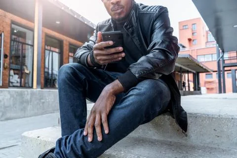 Close up of dark-skinned man looking at mobile phone screen. Stock Photos