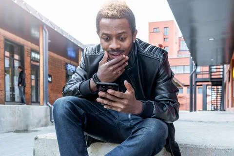 Close up of dark-skinned man looking at mobile phone screen. Stock Photos