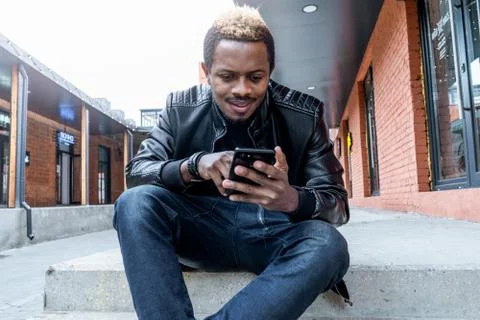 Close up of dark-skinned man looking at mobile phone screen. Stock Photos