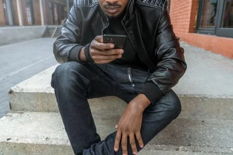 Close up of dark-skinned man looking at mobile phone screen. Stock Photos