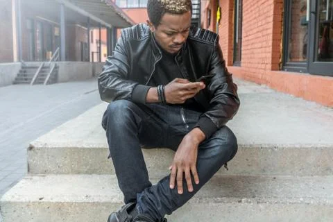 Close up of dark-skinned man looking at mobile phone screen. Stock Photos