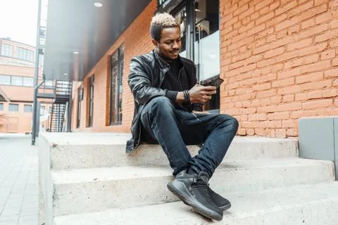 Close up of dark-skinned man looking at mobile phone screen. Stock Photos