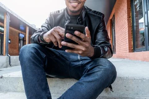 Close up of dark-skinned smiling man looking at mobile phone screen. Foto stock