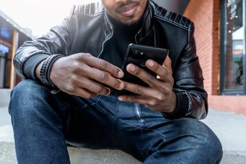 Close up of dark-skinned smiling man looking at mobile phone screen. Foto stock