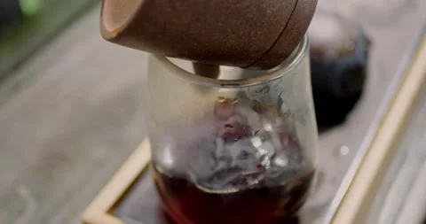 Close-up of dark tea being poured from a clay teapot into... Vidéo 316914771