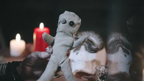 Close up of dark witch piercing voodoo doll with pins Stock Footage 136887257