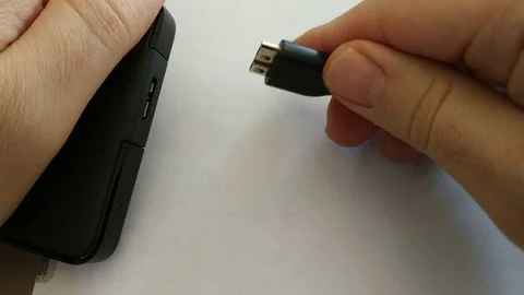 Close-up of data cable connection to portable hard disk. The left hand grabs the Stock Footage 104045997