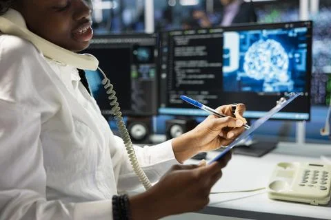 Close up of data center operator taking notes while talking in phone call Stock Photos