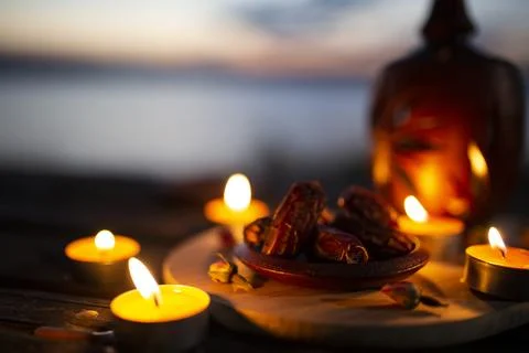 Close-up of dates and burning tealights with a lantern at twilight Stock Photos