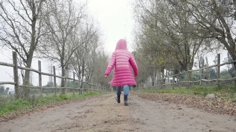 Close up de botas caminando en tierra, luego nina de abrigo rosado se aleja  Stock Footage 165419495