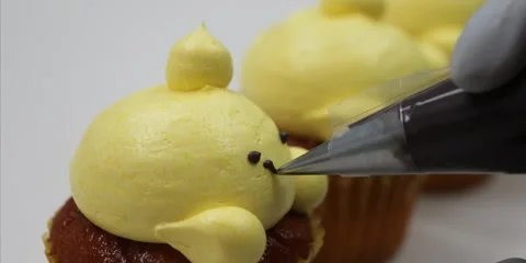 Close Up of Decorating Cute Chick Cupcake with Black Icing Stock Footage 343588822