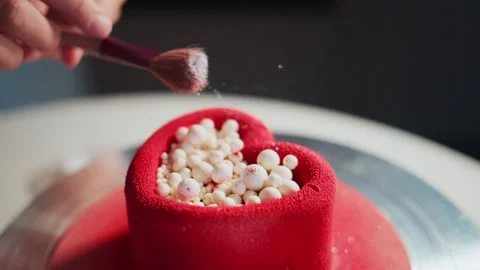 Close-up of decorating a red heart cake with pearl-like toppings Stock Footage 336046559