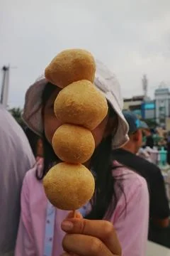 Close-up of deep-fried round dough balls on a skewer held by a child Stock Photos