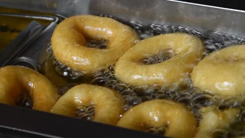 Close up deep frying ring donuts in oil Stockbeeldmateriaal 154005695