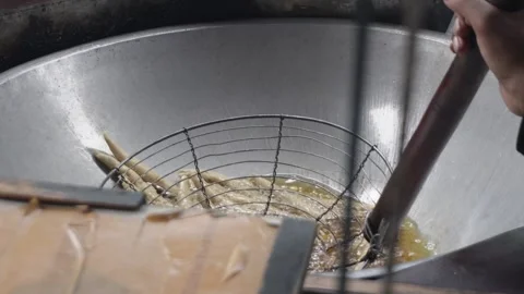 Close up of deep frying traditional snacks or dough sticks in bubbling hot cooki Video stock 337871932