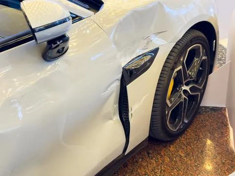 Close up of a deep scratch and dent on a white car door and a wing, showing Stock-Fotos