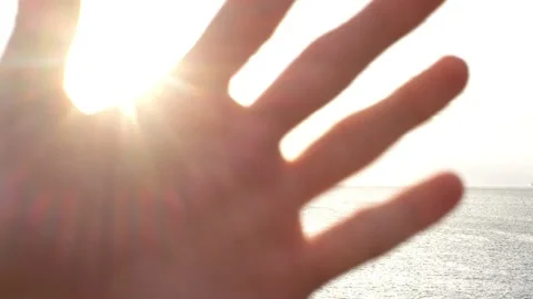 Close up of defocused hand passing in front of the camera with the sunset and th Stock Footage 141652595