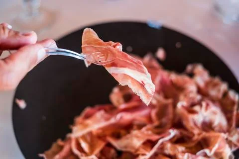 Close up of defocused hands taking and serving resh tasty ham from a black tr Stock Photos