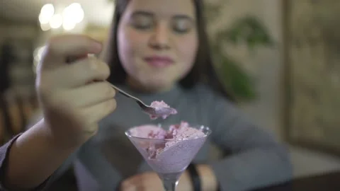 Close up defocused view on chubby brunette teenage girl eating violet color ice  Stockbeeldmateriaal 137538369