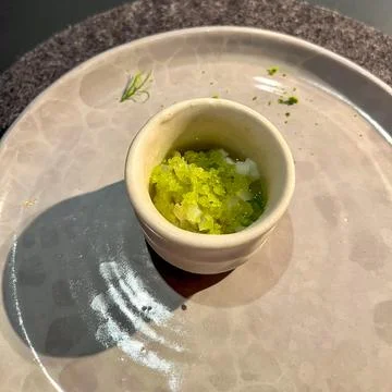 Close-up of a delicate culinary dish featuring a small ceramic bowl of whit.. Stock Photos