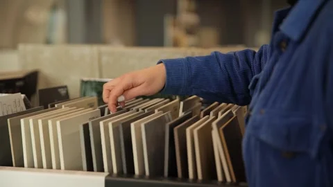Close-up of a delicate female hand choosing a ceramic tile from samples. Stock Footage 304941273