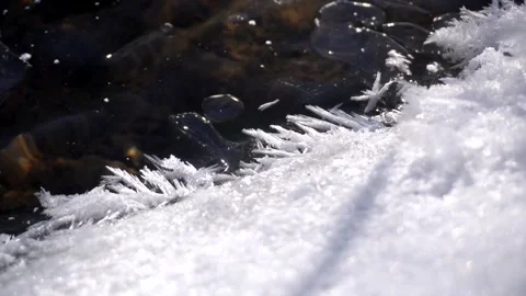 Close up of delicate ice crystals forming on the edge of a frozen creek Video stock 342212272