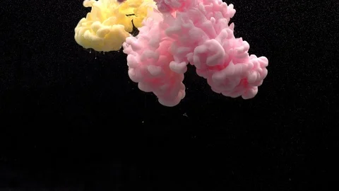 Close-up of delicate pink and yellow paints pouring into water Stock Footage 114321972
