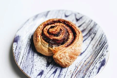 Close up of delicious cinnamon roll in a printed plate. Stock Photos