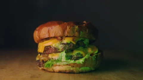 Close-up of a delicious double cheeseburger with melted cheddar cheese, juicy Stock Footage 307707028