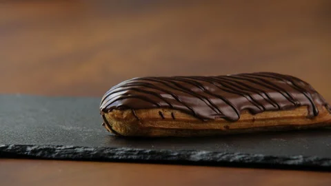 Close-up of a delicious eclair covered with chocolate glaze 스톡 동영상 168188881