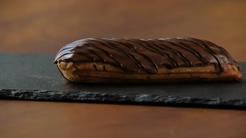 Close-up of a delicious eclair covered with chocolate glaze 스톡 동영상 168189041