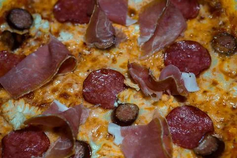 Close-up of a delicious pizza topped with pepperoni, prosciutto and melted .. Stock Photos