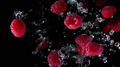 Close up of delicious raspberries bouncing up with splashes of water Stock Footage 139963156