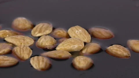 Close-up of delicious roasted almonds falling into chocolate syrup Video stock 60189055