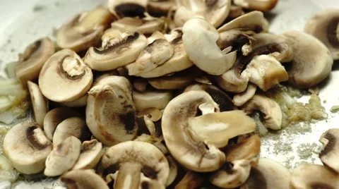Close up of delicious sliced button mushrooms being stir-fried fried with oni Stock Footage 68752877