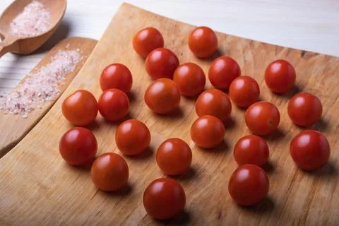 Close-up of delicious small red cherry tomatoes around a large wooden spoon w 写真素材