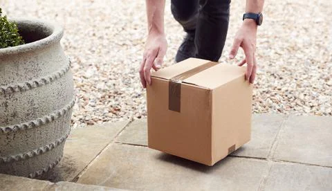 Close Up Of Delivery Driver Putting Package On Doorstep Outside House Stock Photos