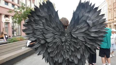 Close up demon with black wings walks down the street among people on the street Stock Footage 283625867