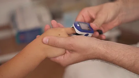 Close-up demonstration video of a doctor using finger pulse oximeter. Pediatric Stock Footage 114075773