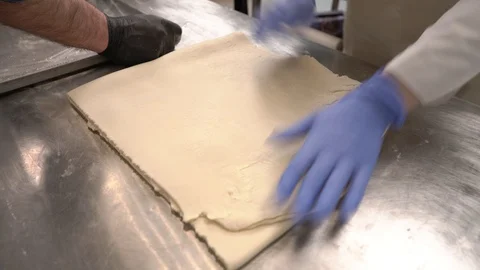A close-up demonstration video of an expert chef squaring laminated dough, and 動画素材 106377138