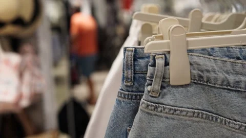 Close-up of denim jeans hanging on a rack in a clothing store Stock Footage 319630867