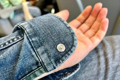 Close-up of a denim shirt cuff with a button. Stock Photos