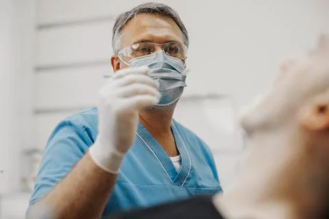 Close up of dentist in blue uniform checking up client teeth health condition. Stock Photos