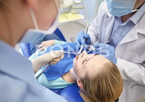 Close Up Of Dentist Treating Female Patient Teeth